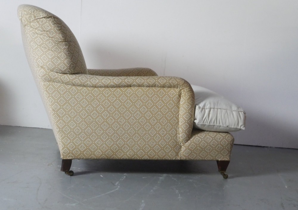 A pair of large upholstered armchairs in beige patterned fabric with deep white down cushions and brass castors on tapered timber feet. View V