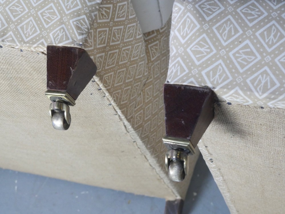 A pair of large upholstered armchairs in beige patterned fabric with deep white down cushions and brass castors on tapered timber feet. View IX