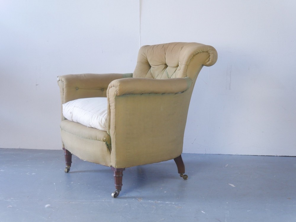 A 19th-century Victorian armchair upholstered in olive fabric with a button-backed scroll back, turned timber front legs on brass castors, and a fitted seat cushion.