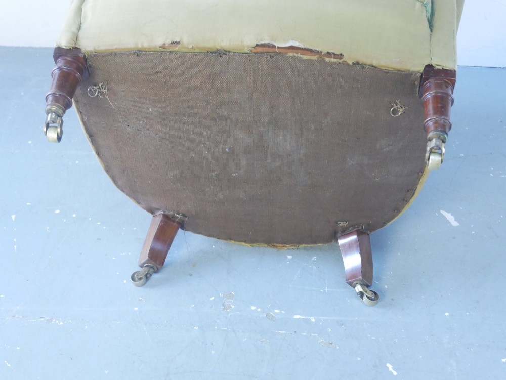 A 19th-century Victorian armchair upholstered in olive fabric with a button-backed scroll back, turned timber front legs on brass castors, and a fitted seat cushion. View VI