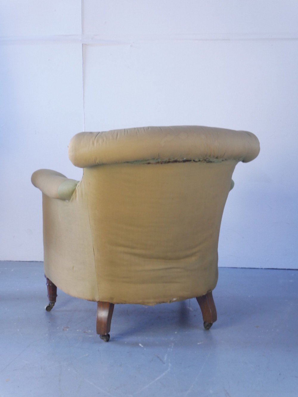 A 19th-century Victorian armchair upholstered in olive fabric with a button-backed scroll back, turned timber front legs on brass castors, and a fitted seat cushion. View VII