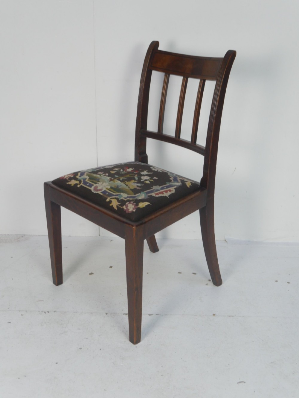 A set of six dark mahogany Georgian dining chairs featuring reeded backs and patterned needlepoint tapestry seats arranged on a neutral background. View II