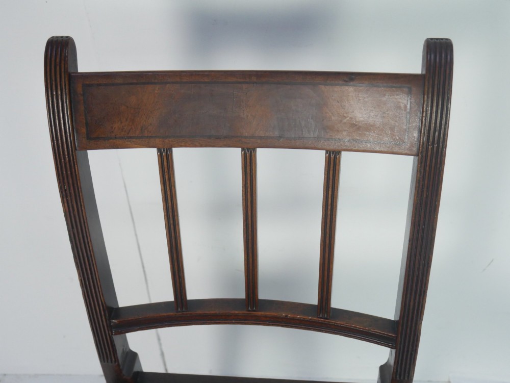A set of six dark mahogany Georgian dining chairs featuring reeded backs and patterned needlepoint tapestry seats arranged on a neutral background. View VII