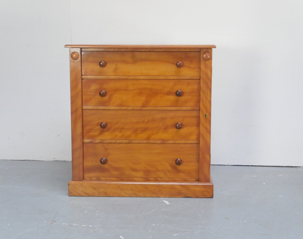 An antique Scottish wooden chest featuring four full-width drawers with dark turned handles and carved roundel details at the upper corners.