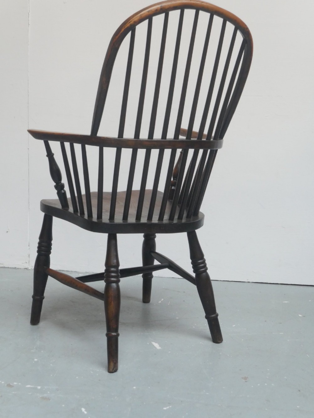 A dark brown wooden Windsor armchair featuring a rounded hoop back, vertical spindles, turned legs, and an H-stretcher. View II