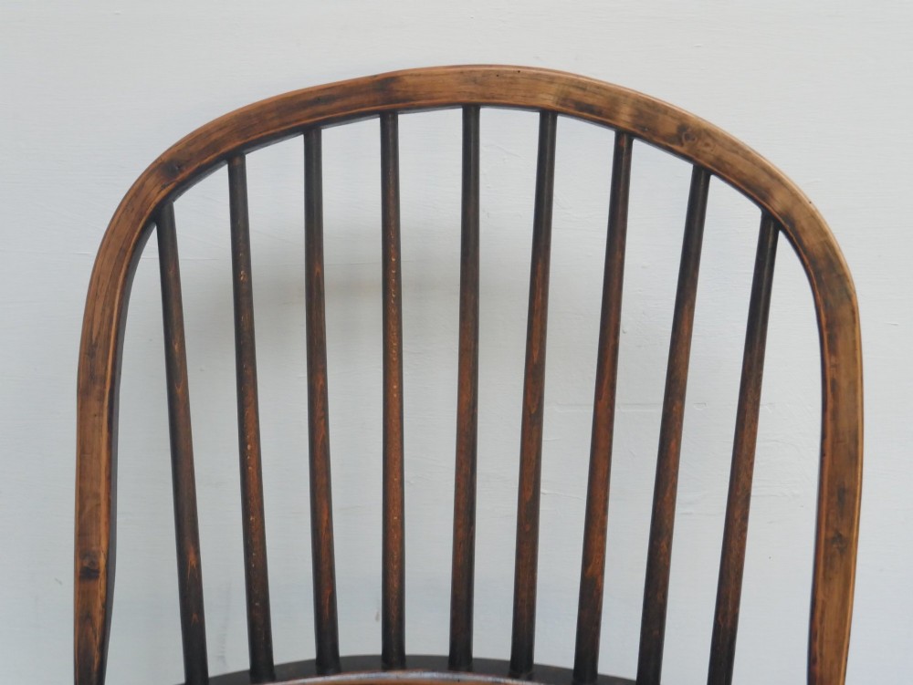 A dark brown wooden Windsor armchair featuring a rounded hoop back, vertical spindles, turned legs, and an H-stretcher. View IV