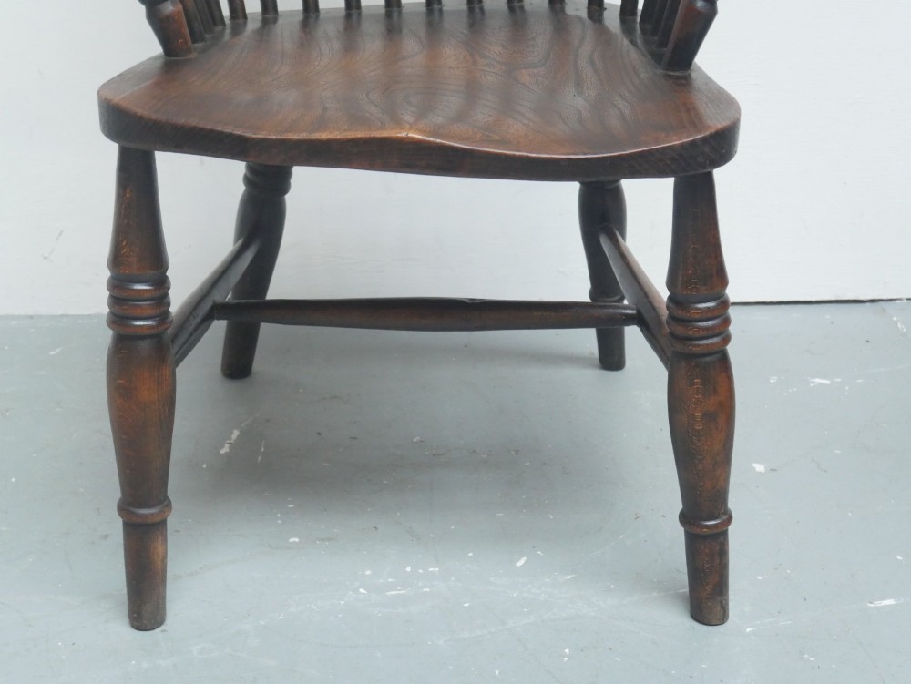 A dark brown wooden Windsor armchair featuring a rounded hoop back, vertical spindles, turned legs, and an H-stretcher. View VI