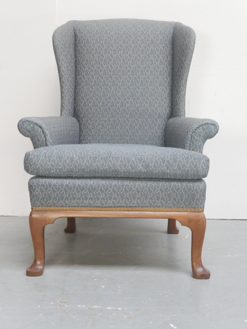 A Scottish wingback armchair upholstered in patterned slate blue fabric featuring mahogany cabriole front legs and brass stud detailing along the lower frame. View III