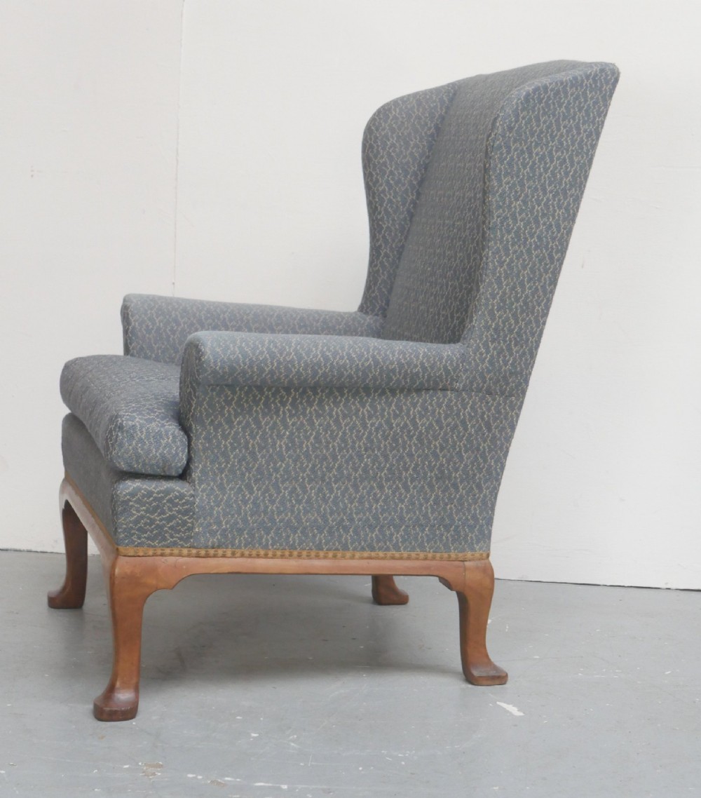 A Scottish wingback armchair upholstered in patterned slate blue fabric featuring mahogany cabriole front legs and brass stud detailing along the lower frame. View IV