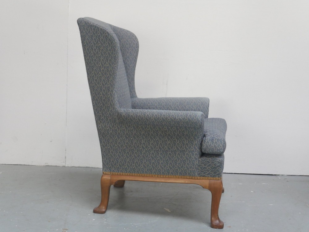 A Scottish wingback armchair upholstered in patterned slate blue fabric featuring mahogany cabriole front legs and brass stud detailing along the lower frame. View V