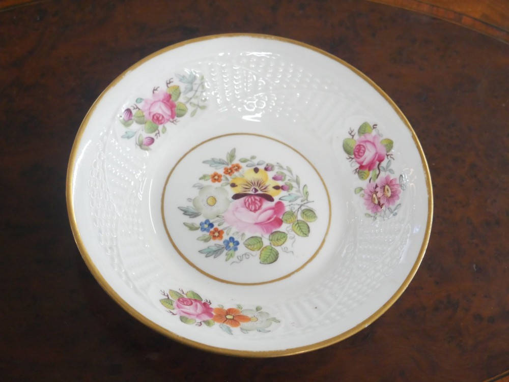 An antique white porcelain teacup and matching saucer featuring hand-painted floral sprays, moulded textured borders, and gilded rim details. View VII