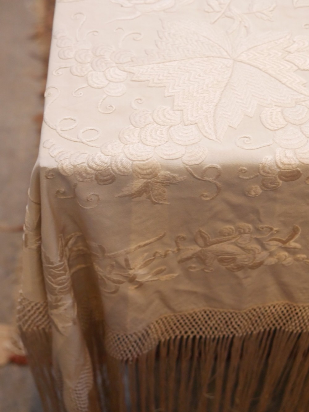 A cream-coloured silk piano shawl featuring tonal floral hand embroidery and deep knotted fringe edge. View III