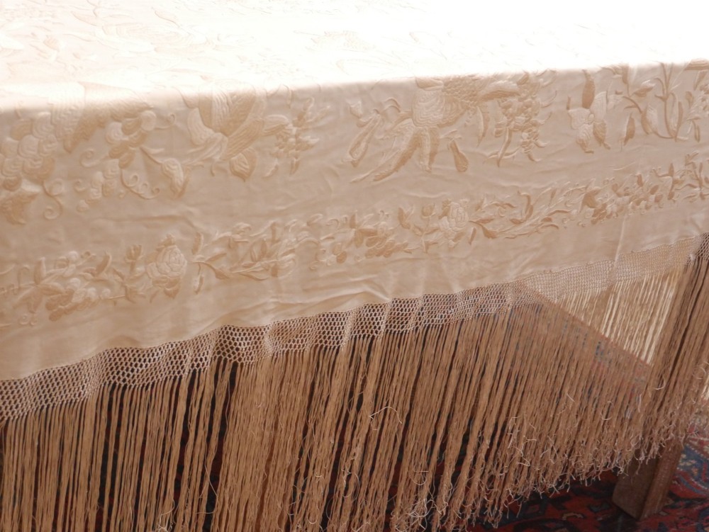 A cream-coloured silk piano shawl featuring tonal floral hand embroidery and deep knotted fringe edge. View IV