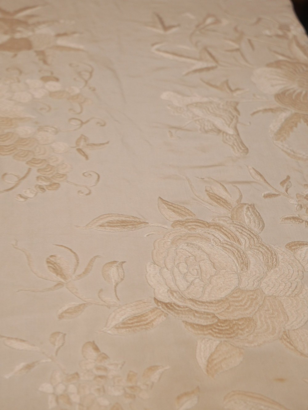 A cream-coloured silk piano shawl featuring tonal floral hand embroidery and deep knotted fringe edge. View V