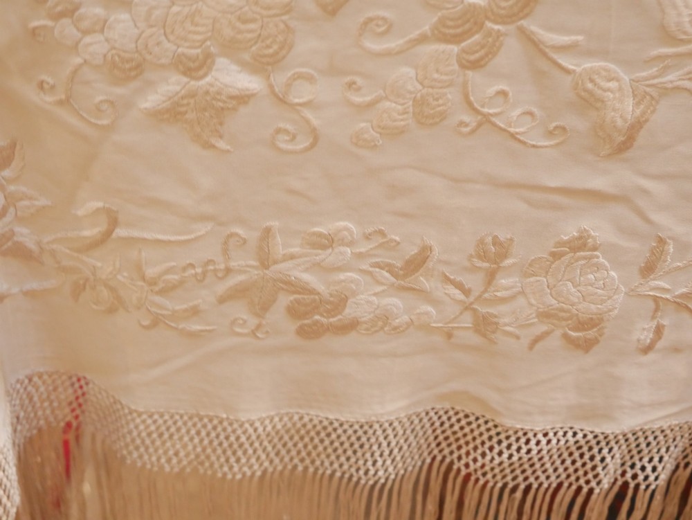A cream-coloured silk piano shawl featuring tonal floral hand embroidery and deep knotted fringe edge. View VIII