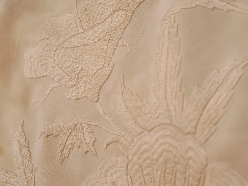 A cream-coloured silk piano shawl featuring tonal floral hand embroidery and deep knotted fringe edge. View X