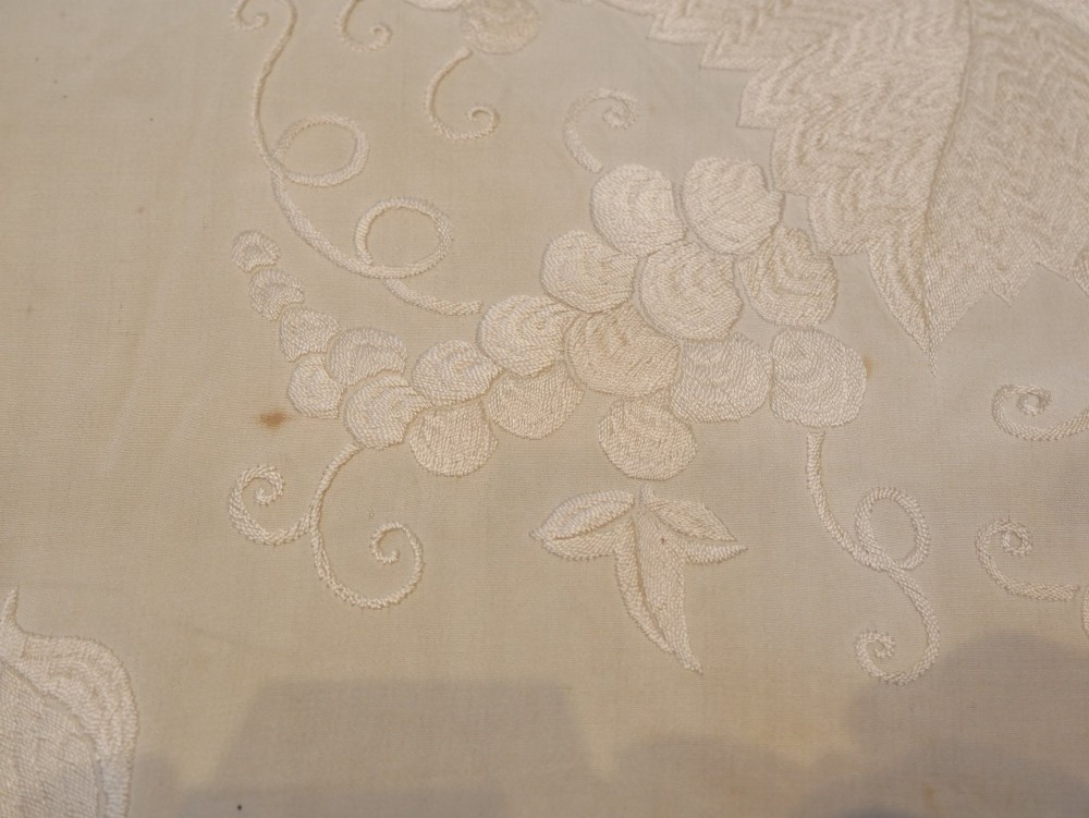 A cream-coloured silk piano shawl featuring tonal floral hand embroidery and deep knotted fringe edge. View XII