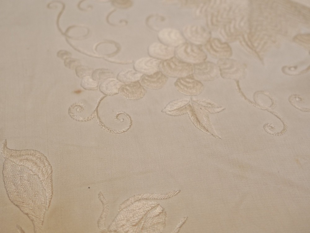A cream-coloured silk piano shawl featuring tonal floral hand embroidery and deep knotted fringe edge. View XIII
