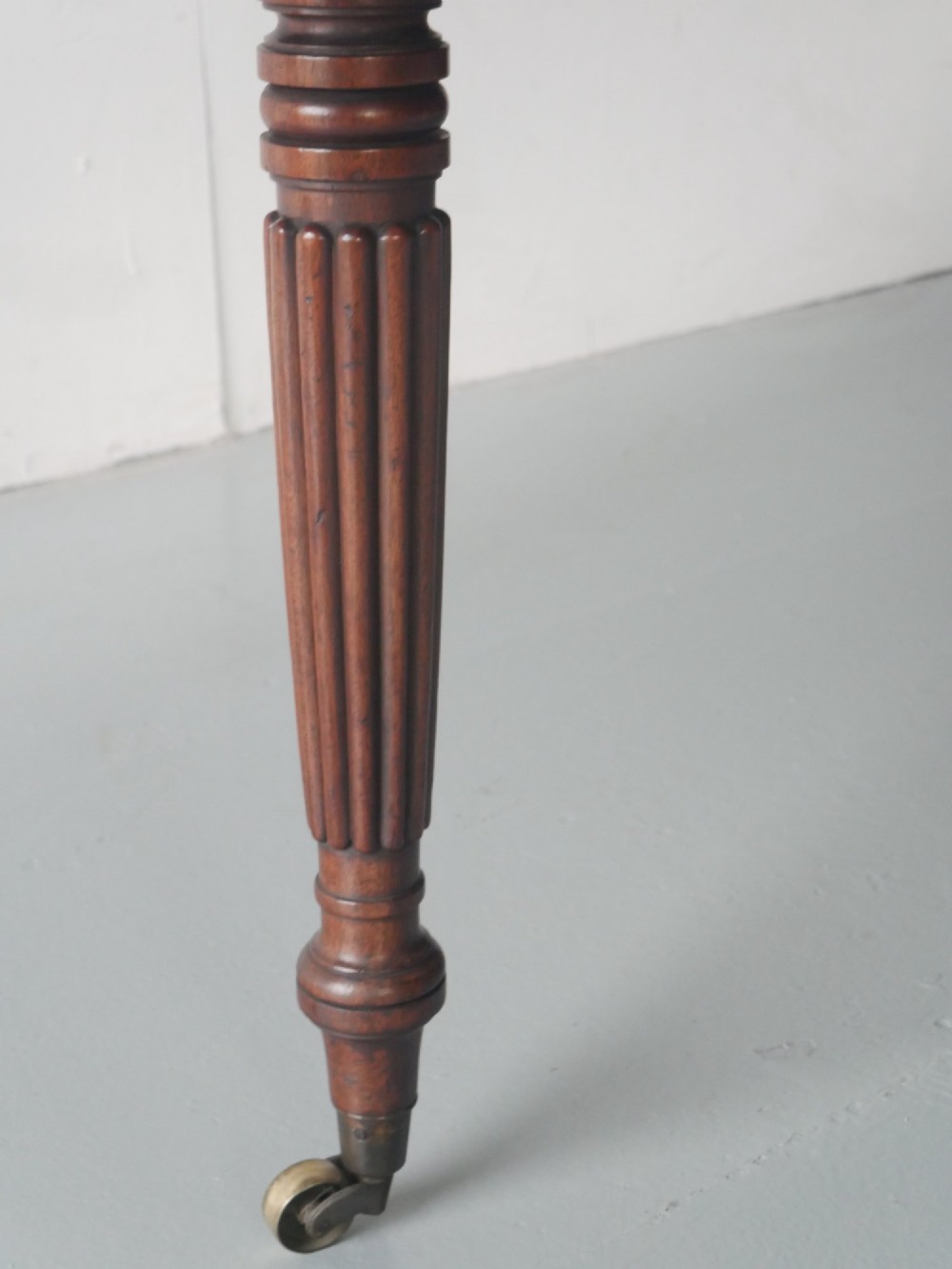 A large antique Regency mahogany extending dining table featuring rounded corners, removable leaves, and reeded legs with brass castors. View X