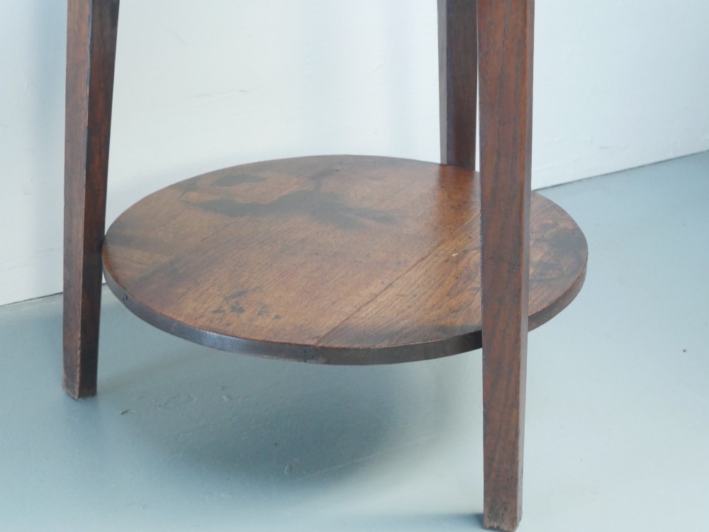 An antique oak cricket table featuring a circular top, three splayed legs, a triangular apron, and a lower circular undertier. View V