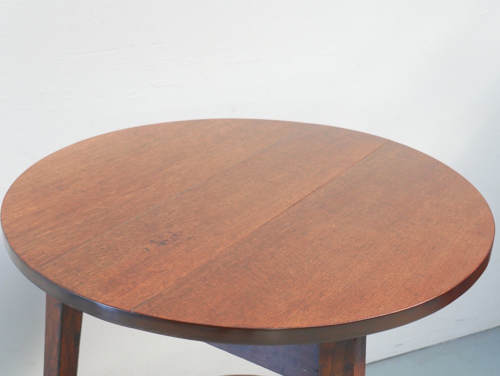An antique oak cricket table featuring a circular top, three splayed legs, a triangular apron, and a lower circular undertier. View VI