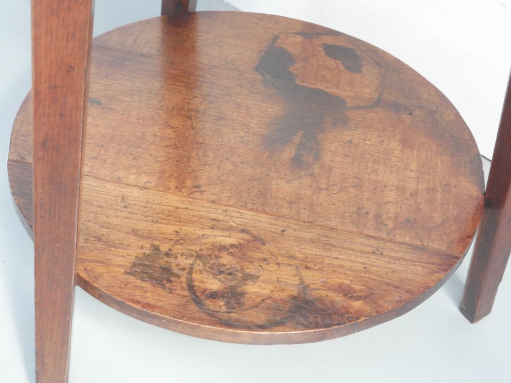 An antique oak cricket table featuring a circular top, three splayed legs, a triangular apron, and a lower circular undertier. View VIII