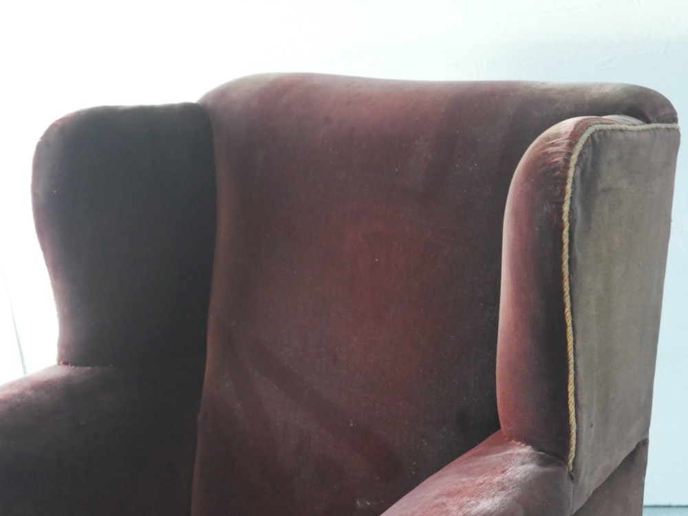 A high-backed antique wing armchair upholstered in deep burgundy velvet with corded piping details and turned wood front legs. View III