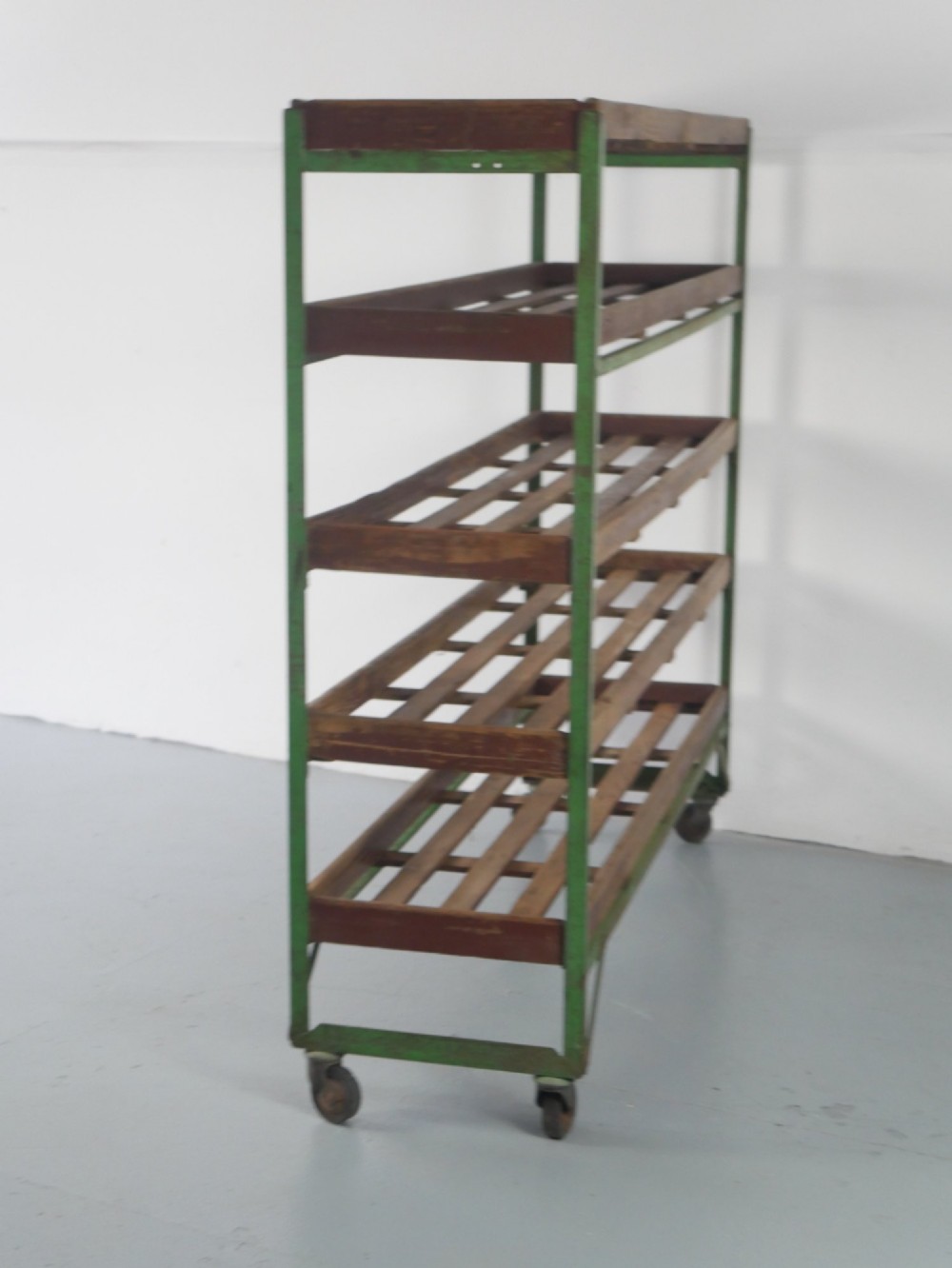 An industrial multi-tiered storage rack featuring slatted wooden shelves within a green painted metal frame fitted with castors. View II