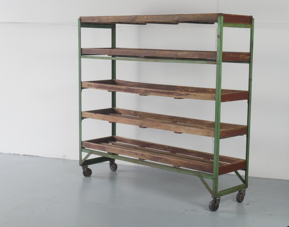 An industrial multi-tiered storage rack featuring slatted wooden shelves within a green painted metal frame fitted with castors. View III