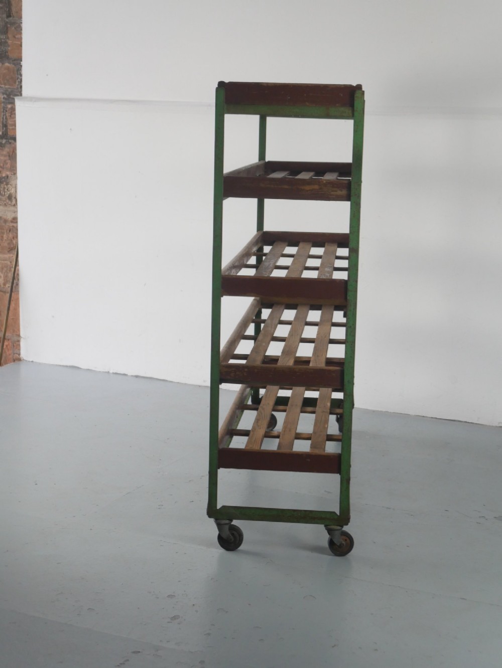 An industrial multi-tiered storage rack featuring slatted wooden shelves within a green painted metal frame fitted with castors. View VII