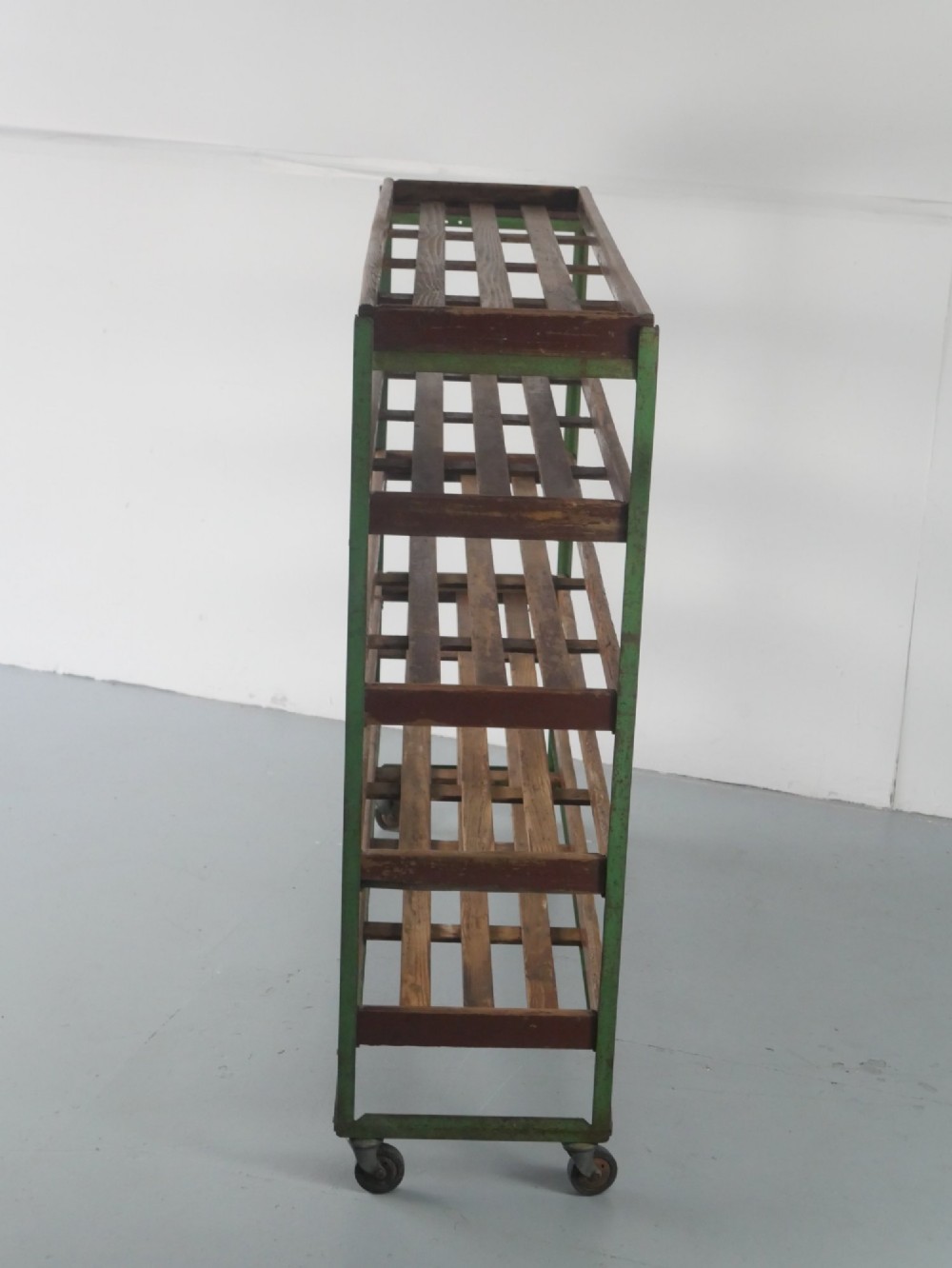 An industrial multi-tiered storage rack featuring slatted wooden shelves within a green painted metal frame fitted with castors. View VIII