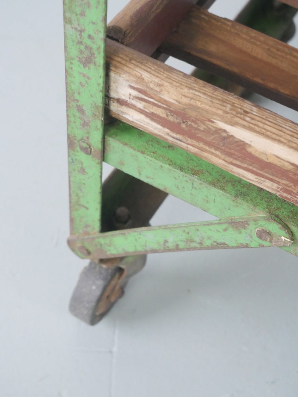 An industrial multi-tiered storage rack featuring slatted wooden shelves within a green painted metal frame fitted with castors. View IX