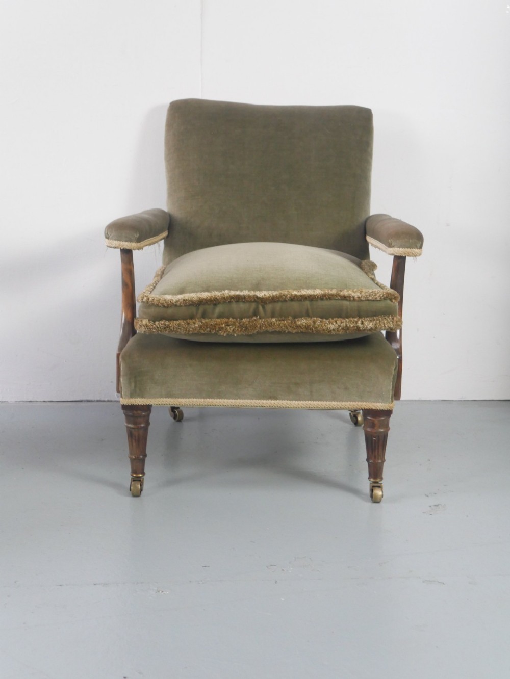 A matched pair of armchairs upholstered in olive green velvet with fringed seat cushions and turned front legs on brass castors. View III
