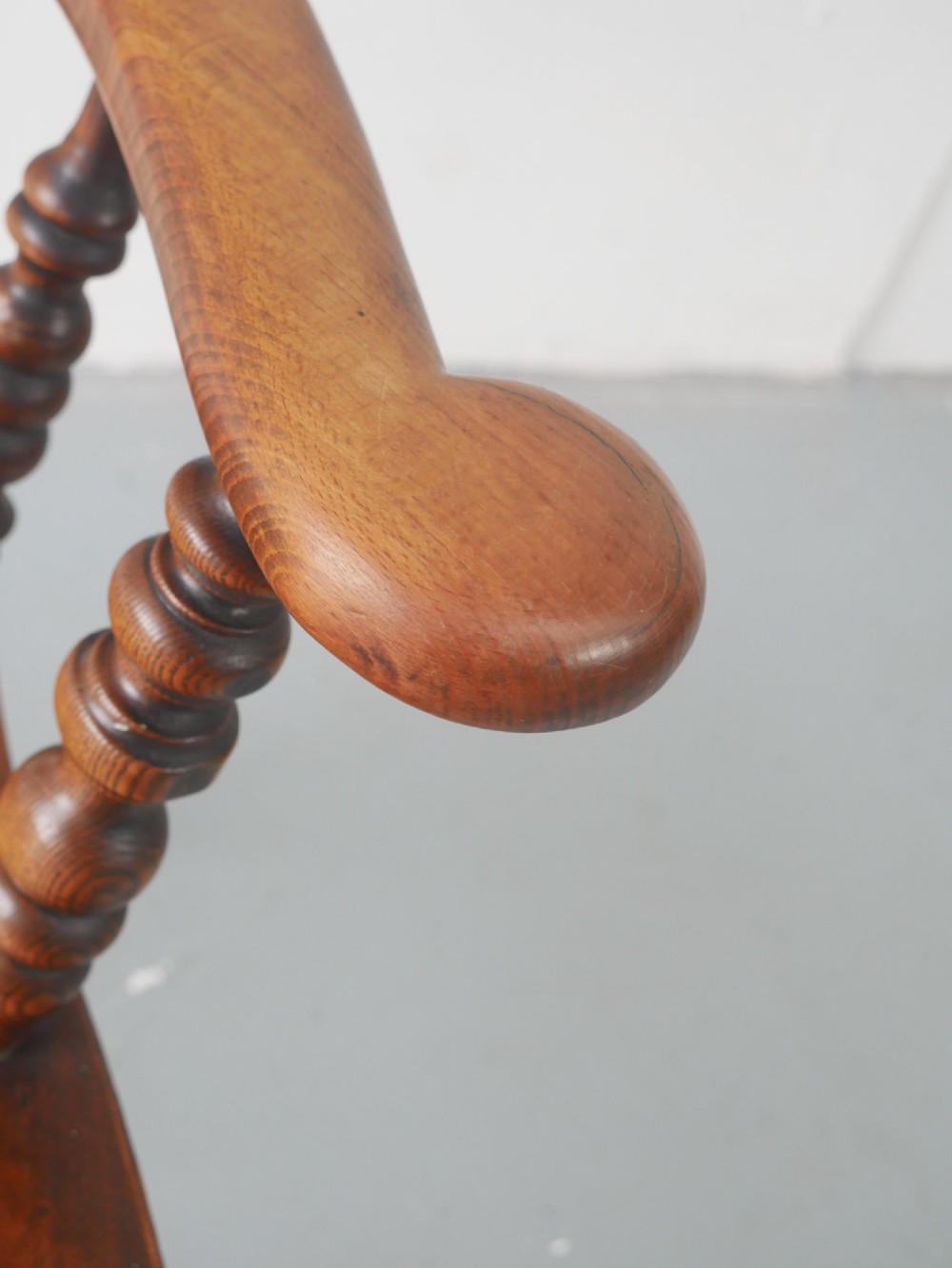 A wooden broad-arm Windsor armchair featuring a hoop back, pierced central splat, turned spindles, and a saddle seat. View II
