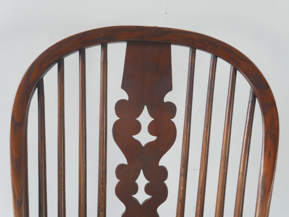 A wooden broad-arm Windsor armchair featuring a hoop back, pierced central splat, turned spindles, and a saddle seat. View IV