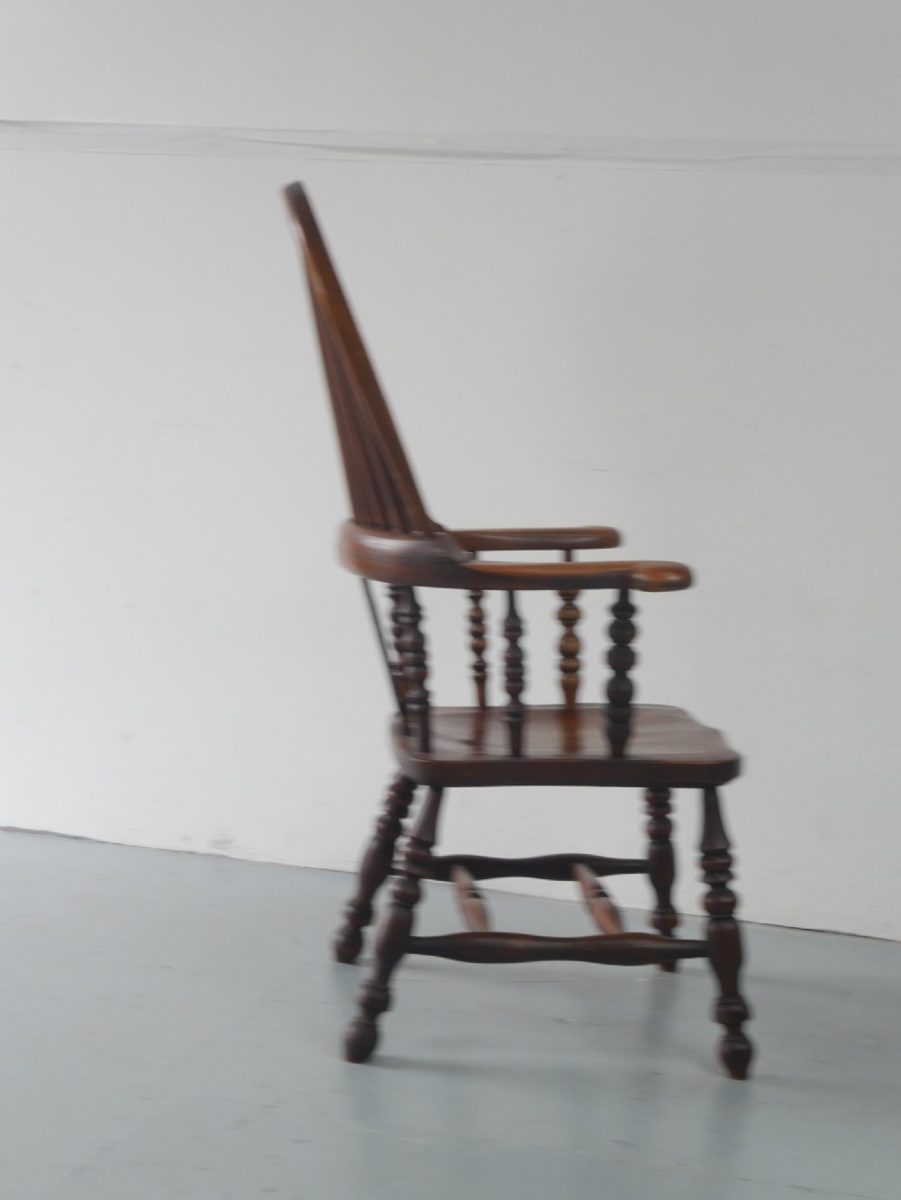 A wooden broad-arm Windsor armchair featuring a hoop back, pierced central splat, turned spindles, and a saddle seat. View X