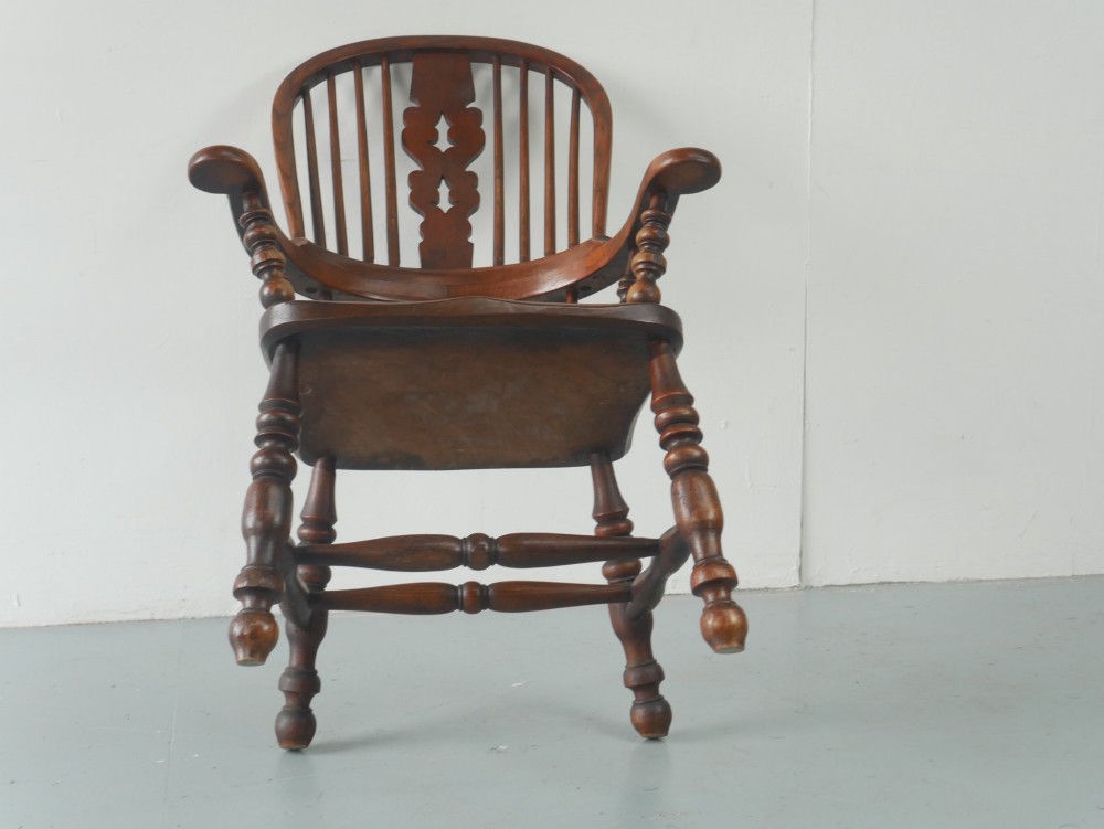 A wooden broad-arm Windsor armchair featuring a hoop back, pierced central splat, turned spindles, and a saddle seat. View XI