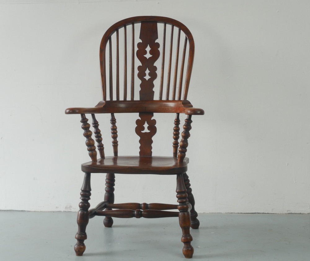 A wooden broad-arm Windsor armchair featuring a hoop back, pierced central splat, turned spindles, and a saddle seat. View XII