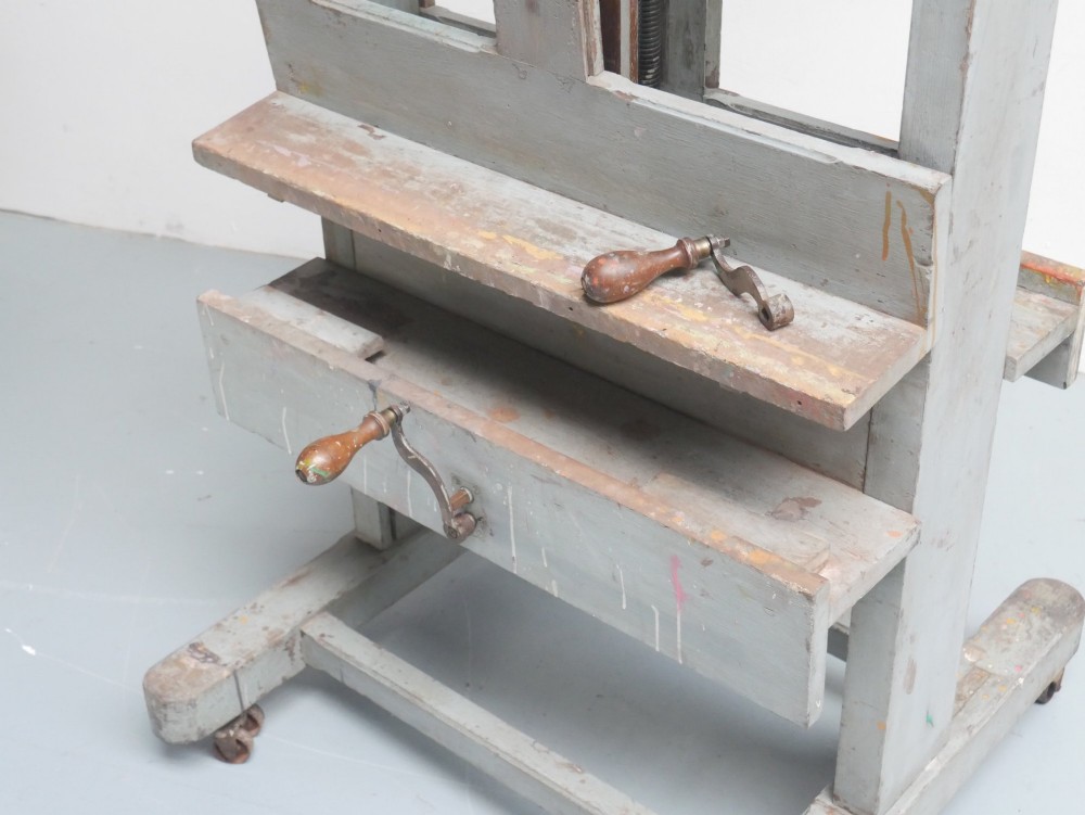 A large floor-standing double-sided timber studio easel with a distressed grey finish, adjustable height mechanism, and metal castor feet. View VIII