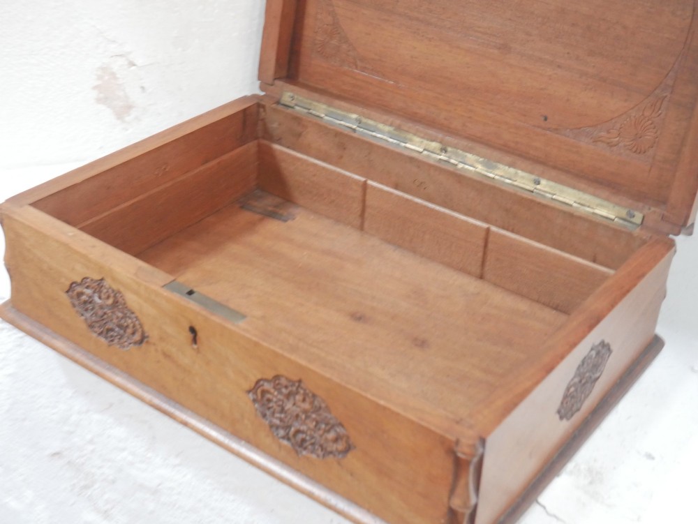 A rectangular Anglo-Indian carved teak box featuring a raised central motif on the lid, carved bamboo-style border trim, and side decorative panels. View III