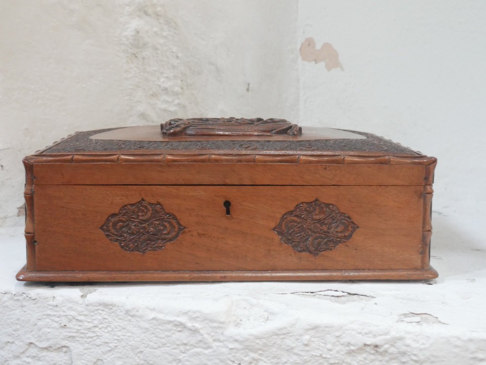 A rectangular Anglo-Indian carved teak box featuring a raised central motif on the lid, carved bamboo-style border trim, and side decorative panels. View VIII