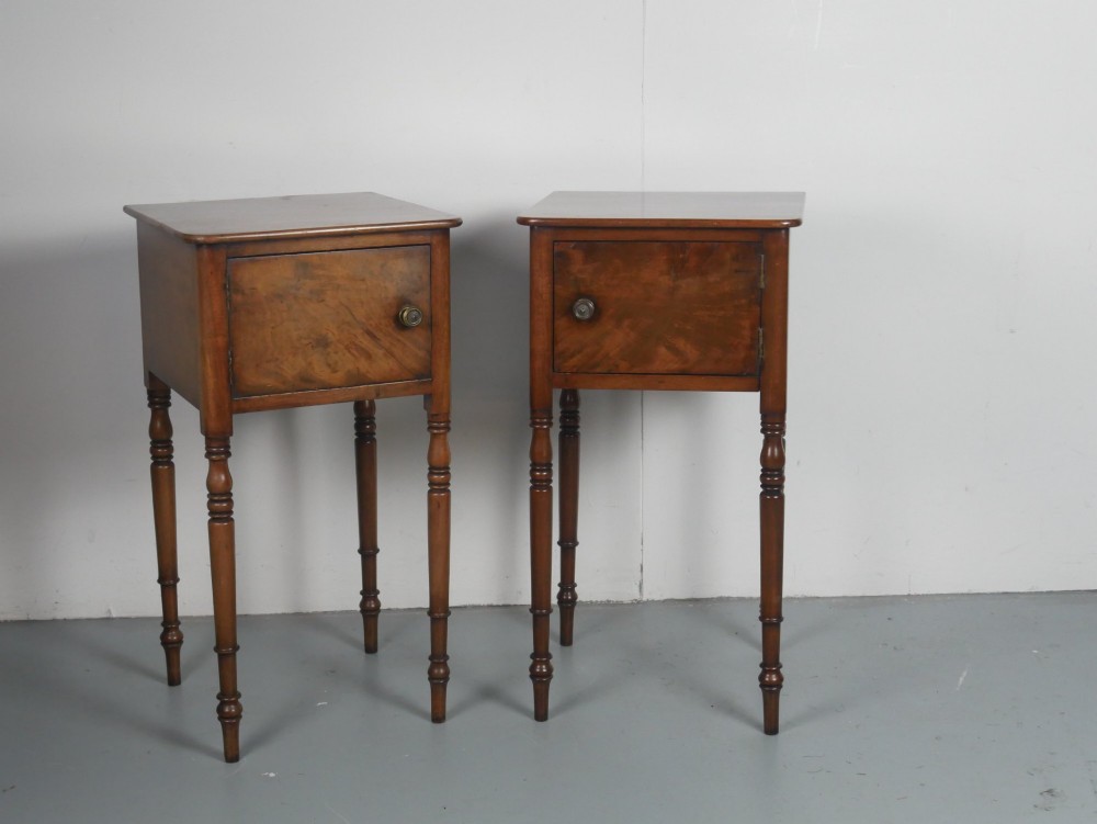 A matching pair of tall mahogany Regency bedside cupboards featuring single panel doors with small handles and slim turned legs.