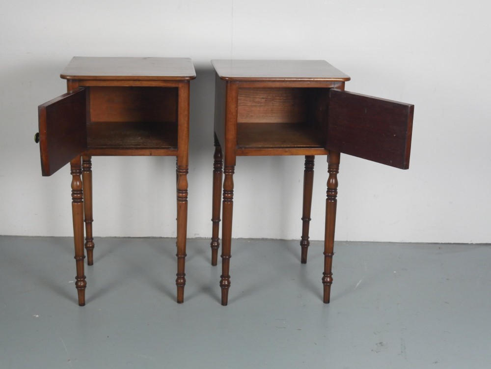 A matching pair of tall mahogany Regency bedside cupboards featuring single panel doors with small handles and slim turned legs. View V