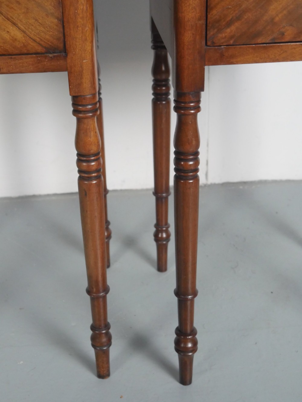 A matching pair of tall mahogany Regency bedside cupboards featuring single panel doors with small handles and slim turned legs. View VII