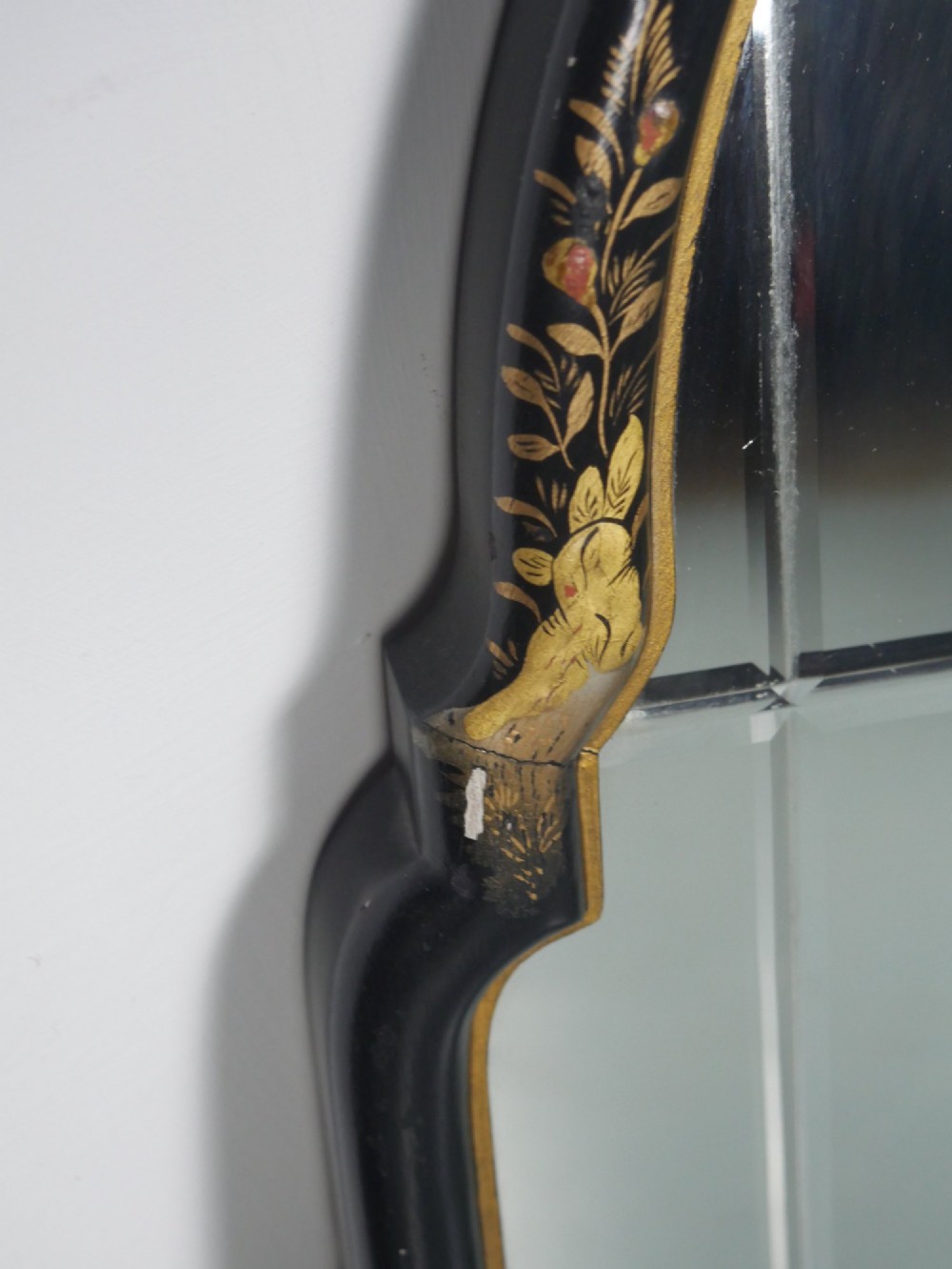 An arched black lacquer wall mirror decorated with gold hand-painted chinoiserie details and sectioned bevelled glass. View III
