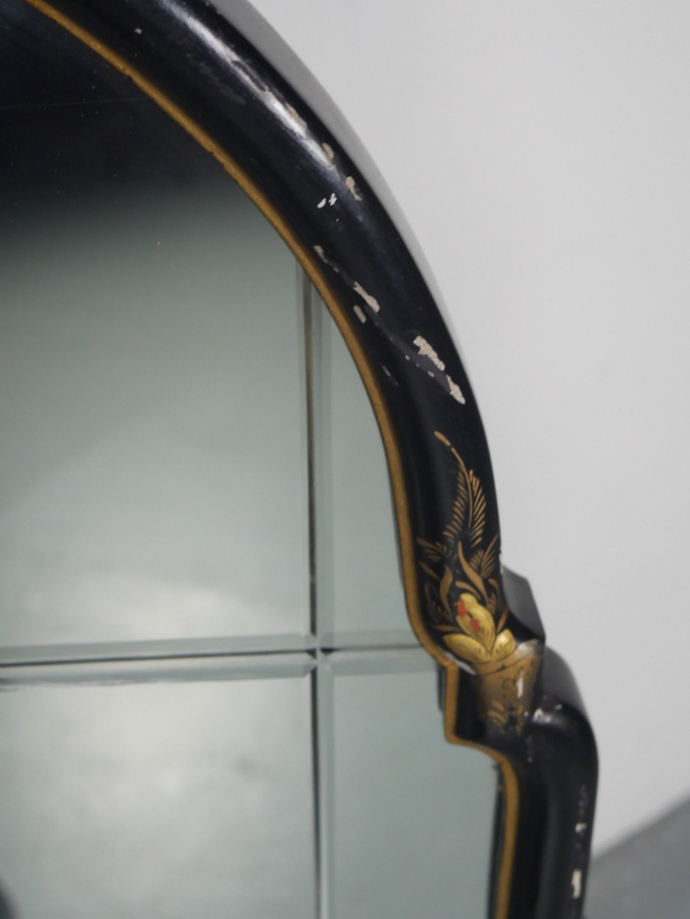 An arched black lacquer wall mirror decorated with gold hand-painted chinoiserie details and sectioned bevelled glass. View X