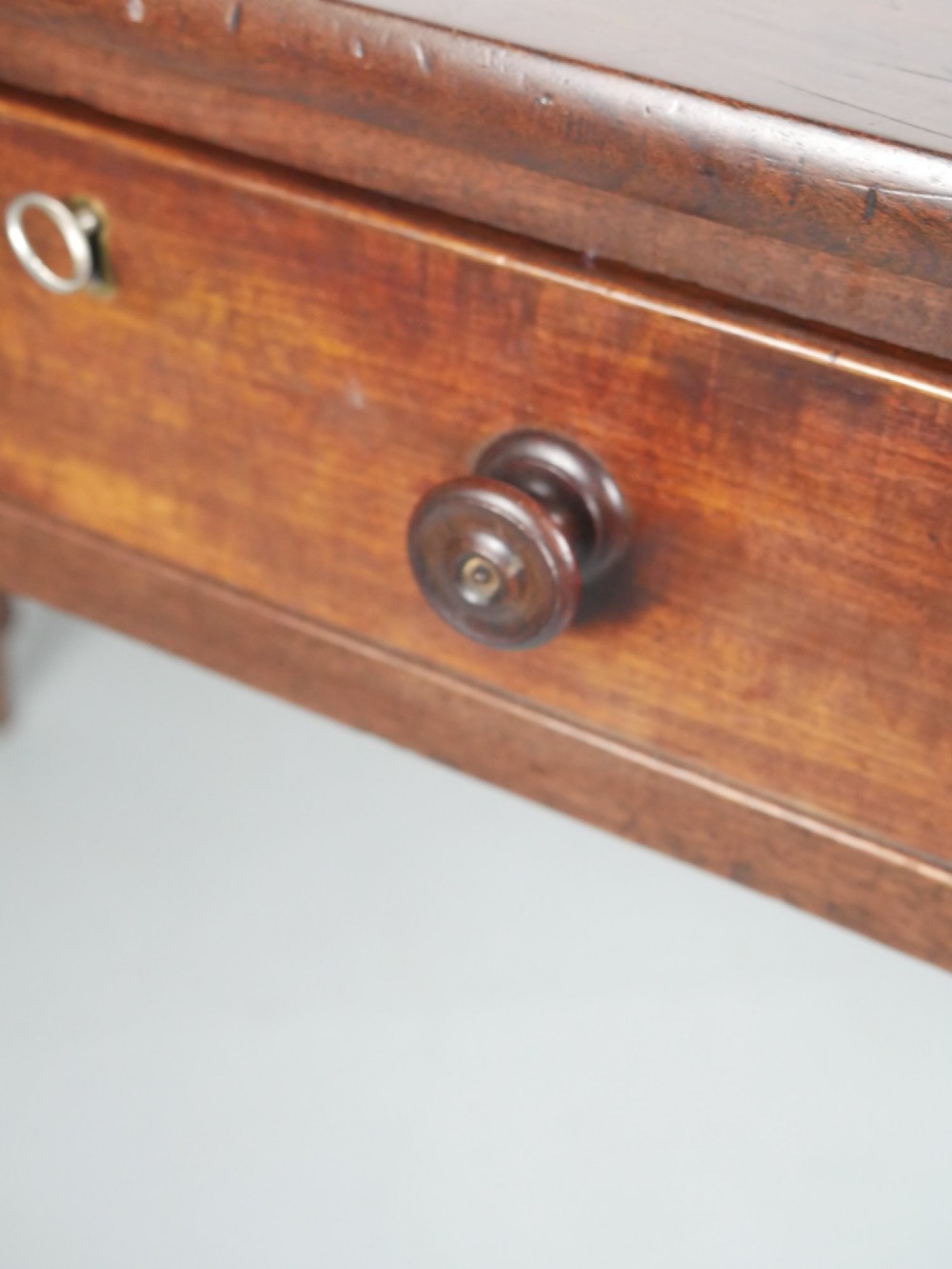 A Regency period mahogany writing table featuring three drawers with wooden knobs, a three-sided gallery rim, and four reeded legs. View VI