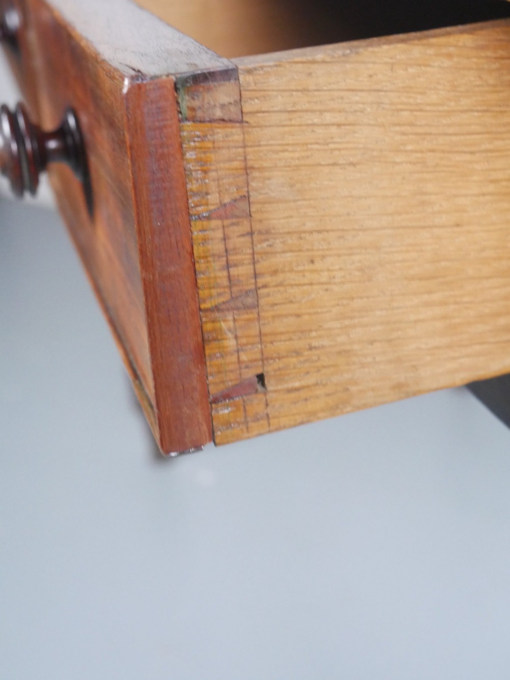 A Regency period mahogany writing table featuring three drawers with wooden knobs, a three-sided gallery rim, and four reeded legs. View VII