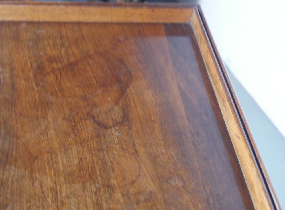 A Regency period mahogany writing table featuring three drawers with wooden knobs, a three-sided gallery rim, and four reeded legs. View X