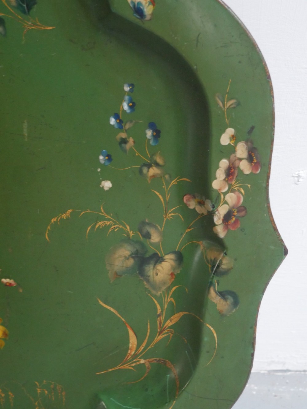 An antique 19th-century olive green painted metal toleware tray featuring a scalloped rim and hand-painted botanical flowers with gilded accents. View III